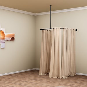 Puede incluir: Un sistema de barra de cortina de metal negro con cortinas beige colgadas. La barra est&aacute; unida al techo y se extiende para crear un recinto cuadrado. Las cortinas est&aacute;n completamente cerradas, creando un espacio privado.