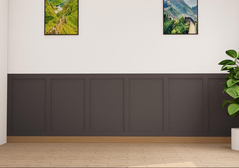 May include: A room with dark brown wainscoting and a light wood floor. There are two framed pictures on the wall, one of a mountain range and one of a green valley. A potted plant is in the corner of the room.
