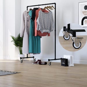 Pode incluir: Cabideiro de metal preto com uma barra superior para pendurar roupas. O cabideiro tem uma base retangular com quatro rodízios. Várias peças de vestuário de diferentes cores estão penduradas, incluindo um trench coat cinza claro e um vestido turquesa.