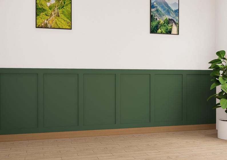 May include: A wall with a white top half and a dark green bottom half. The bottom half is divided into six panels with a wood trim around the edges. There are two framed pictures on the wall, one above the other. The top picture is a landscape scene with green hills and a waterfall. The bottom picture is a landscape scene with a mountain range. There is a potted plant in the corner of the room.