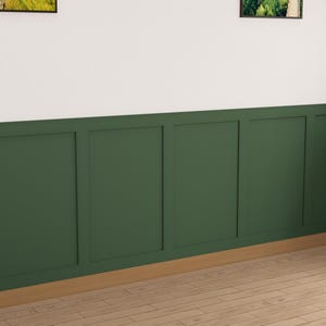 May include: A wall with a dark green wainscot paneling with a white top. The paneling has a raised design with vertical and horizontal lines. The floor is a light wood.