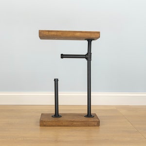 May include: A rustic side table with a wooden top and base, connected by black metal pipes. The table has a unique industrial design, perfect for a living room or bedroom. The wooden top measures approximately 12 inches long.