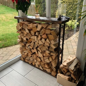 Puede incluir: Un rústico estante de madera y metal para leña con leña apilada. El estante está en una habitación con suelo de baldosas y una ventana con vistas a un césped verde.