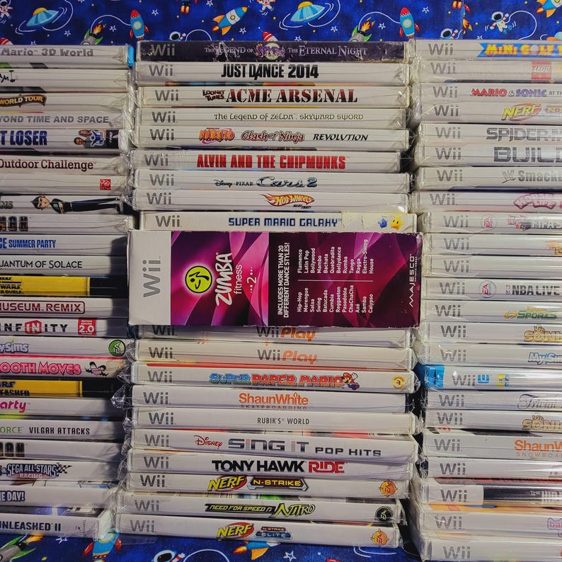 K&ouml;nnte beinhalten: Ein Stapel von &uuml;ber 30 Videospiel-H&uuml;llen f&uuml;r die Nintendo Wii-Konsole. Die H&uuml;llen sind gr&ouml;&szlig;tenteils wei&szlig; mit bunten Spieltiteln und Logos. Einige der Spiele sind Just Dance 2014, Super Mario Galaxy, Zumba Fitness 2 und Tony Hawk Ride.