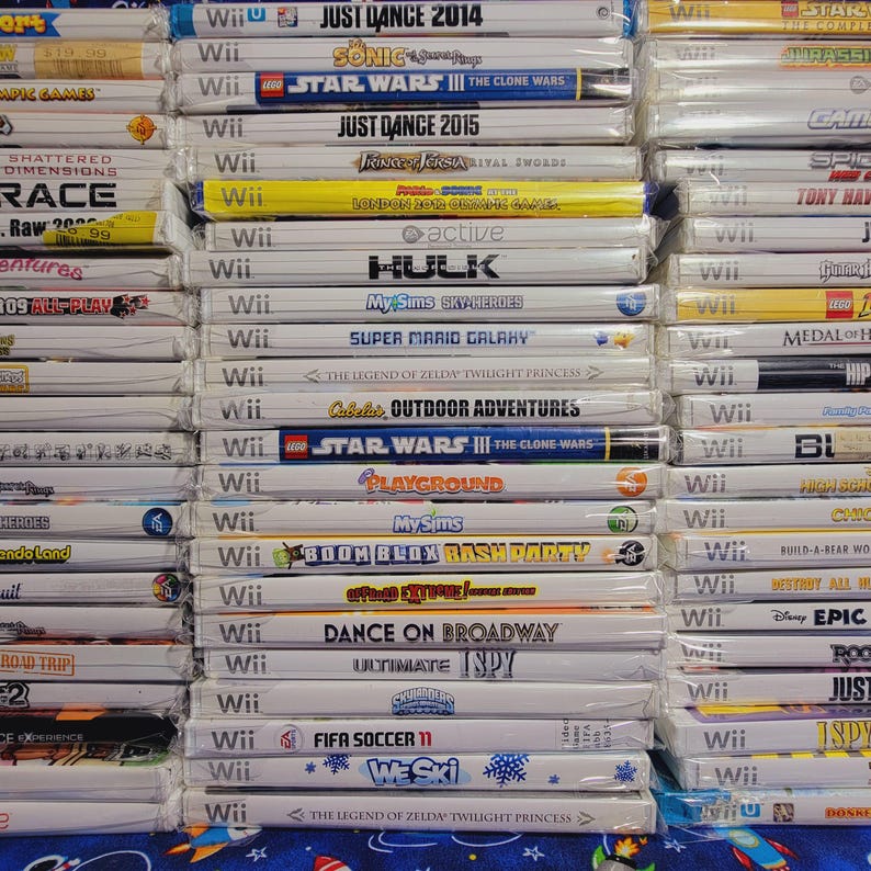 K&ouml;nnte beinhalten: Ein Stapel von 20 Videospiel-H&uuml;llen f&uuml;r die Nintendo Wii-Konsole. Die H&uuml;llen sind gr&ouml;&szlig;tenteils wei&szlig; mit bunten Spieltiteln und Logos. Einige der Spiele sind Just Dance 2014, Star Wars III: The Clone Wars, Super Mario Galaxy und The Legend of Zelda: Twilight Princess.