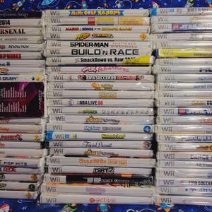 K&ouml;nnte beinhalten: Ein Stapel von &uuml;ber 30 Videospiel-H&uuml;llen f&uuml;r die Nintendo Wii-Konsole. Die H&uuml;llen sind wei&szlig; mit bunten Spieltiteln und Logos. Einige der Spiele sind "Mario & Sonic bei den Olympischen Spielen", "Spider-Man: Shattered Dimensions", "Build 'n Race", "SmackDown vs. Raw 2009", "FIFA Fussball 09", "NBA Live 08", "Sonic Unleashed", "My Sims SkyHeroes", "Nintendo Land", "Trivial Pursuit", "Shaun White: Road Trip", "DIRT 2", "The Hip Hop Dance Experience" und "Baby Sitting: Active".
