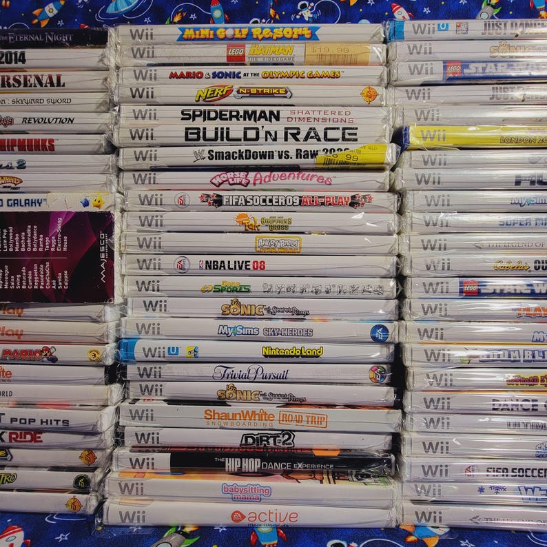 K&ouml;nnte beinhalten: Ein Stapel von &uuml;ber 30 Videospiel-H&uuml;llen f&uuml;r die Nintendo Wii-Konsole. Die H&uuml;llen sind wei&szlig; mit bunten Spieltiteln und Logos. Einige der Spiele sind "Mario & Sonic bei den Olympischen Spielen", "Spider-Man: Shattered Dimensions", "Build 'n Race", "SmackDown vs. Raw 2009", "FIFA Fussball 09", "NBA Live 08", "Sonic Unleashed", "My Sims SkyHeroes", "Nintendo Land", "Trivial Pursuit", "Shaun White: Road Trip", "DIRT 2", "The Hip Hop Dance Experience" und "Baby Sitting: Active".