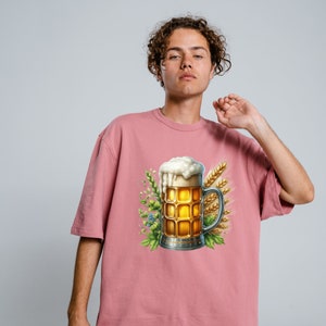 May include: A pink t-shirt with a graphic of a beer stein with a foamy head, surrounded by wheat stalks and green leaves.