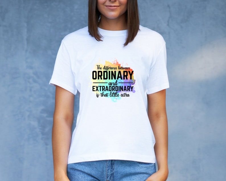 K&ouml;nnte beinhalten: Wei&szlig;es T-Shirt mit einem Regenbogen-Aquarellhintergrund und dem Text "The difference between ORDINARY and EXTRAORDINARY is that little extra."