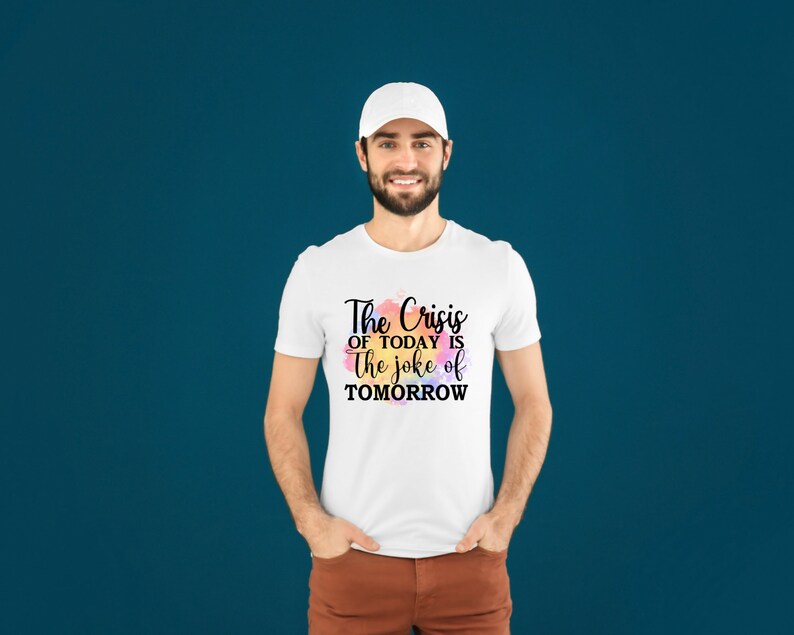 K&ouml;nnte beinhalten: Wei&szlig;es T-Shirt mit einem schwarzen Aufdruck, der "The Crisis of Today is the Joke of Tomorrow" lautet.