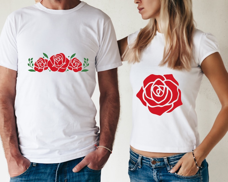 K&ouml;nnte beinhalten: Wei&szlig;e T-Shirts mit roten Rosenmustern. Ein Shirt zeigt drei Rosen mit gr&uuml;nen Bl&auml;ttern, das andere eine einzelne gro&szlig;e Rose. Die Shirts sind kurz&auml;rmlig und f&uuml;r Freizeitkleidung geeignet.