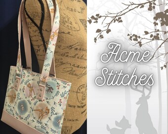 May include: A tote bag with a light pink base and straps. The main body of the bag features a white fabric with a pattern of deer, flowers, and leaves in pastel colors. The bag has a rectangular shape and is displayed on a mannequin.