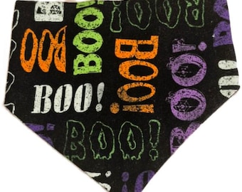 May include: Black Halloween dog bandana with the word "BOO!" in orange, green, white, and purple. The bandana is triangular and features a repeating pattern of the word "BOO!" in a distressed font.