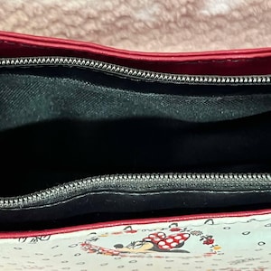 Puede incluir: El interior de un bolso de mano con estampado rojo y blanco con una cremallera negra y un forro de tela negro.