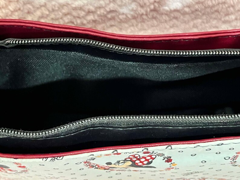 Puede incluir: El interior de un bolso de mano con estampado rojo y blanco con una cremallera negra y un forro de tela negro.