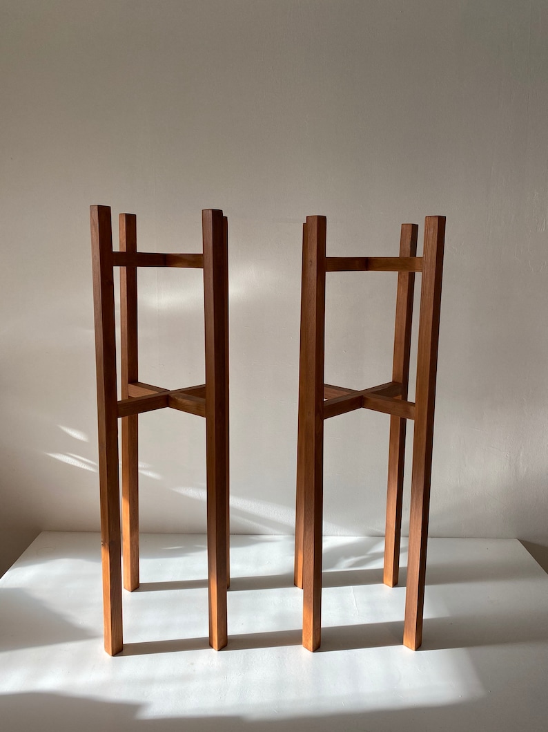 May include: Two wooden plant stands with a simple, rectangular design. The stands are made of natural wood and have a rustic, farmhouse style.