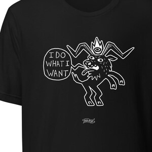 Puede incluir: Camiseta negra con una ilustración de dibujos animados en blanco de una criatura parecida a una cabra que lleva una corona y saca la lengua. La criatura sostiene un bocadillo de diálogo con el texto "I DO WHAT I WANT".