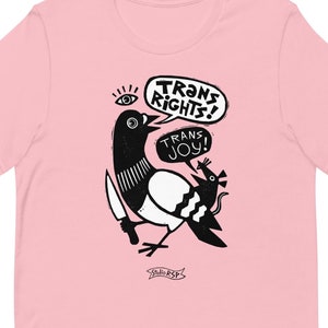 May include: Pink t-shirt with a black and white illustration of a bird holding a knife and a rat. The bird has a speech bubble that says "Trans Rights!" and the rat has a speech bubble that says "Trans Joy!"