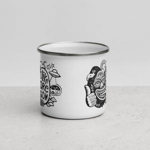 Puede incluir: Una taza de esmalte blanco con borde plateado que presenta ilustraciones gr&aacute;ficas en negro. El dise&ntilde;o incluye una criatura de tres ojos haciendo un gesto de pulgar hacia arriba, un OVNI, una caravana y el texto I LIKE OREGON en una fuente circular.