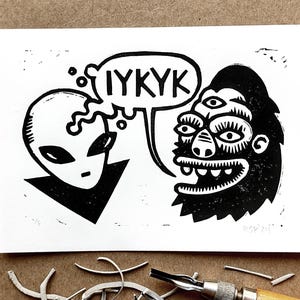 May include: Black and white linocut print of an alien and a three-eyed gorilla with the text "IYKYK" in a thought bubble above the alien.