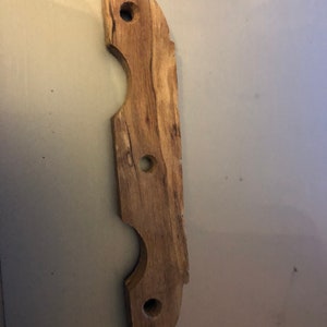 May include: A wooden handle with three holes, likely for a tool or a piece of furniture. The handle is made of light brown wood with a natural grain pattern.