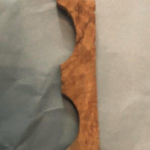 May include: A decorative wooden piece with a unique, intricate design. The piece is brown and has a natural wood grain. It is shaped like a series of arches.