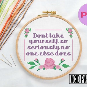 May include: A cross-stitch pattern featuring the phrase "Don't take yourself so seriously no one else does" with pink roses and green leaves. The pattern is displayed in a wooden embroidery hoop on a white surface. The image also includes a pink circle with the word "PDF" in white text.