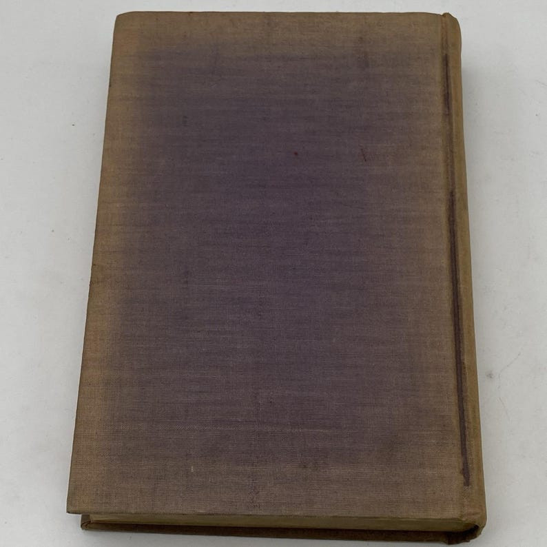 May include: A vintage book with a worn, textured cover. The cover is primarily a muted purple color, with a gradient effect. The edges and spine are a faded brown. The book appears to be well-used, with signs of age.