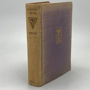 May include: A vintage hardcover book titled "Representative Men" by Emerson. The book has a tan spine with the title and author's name in black. The cover is a faded purple with a gold emblem. The book is in good condition.