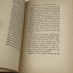 May include: Open book pages with printed text. The text is in black font on aged, off-white paper. The title "MONTAIGNE; OR, THE SKEPTIC" is visible at the top of the right page. The book is open to a section of text.