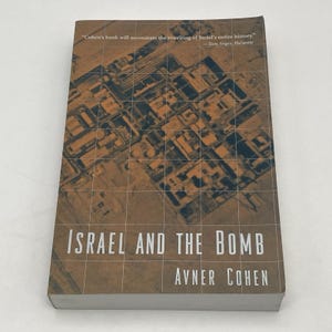 May include: A hardcover book titled "Israel and the Bomb" by Avner Cohen. The cover features an aerial view of a complex with a grid overlay. The book has a quote from Tom Segev, Ha'aretz.