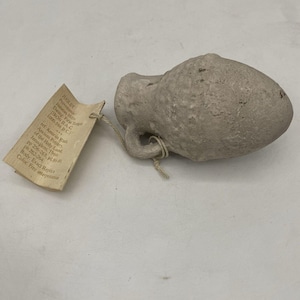 Puede incluir: Una pequeña jarra de cerámica gris con asa. La jarra está etiquetada con información sobre su origen y datación, incluyendo "Judacan Hills", "Dating: First Temple", "1000-586 B.C", y "Iron II A-C".