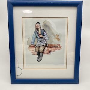 May include: A framed watercolor painting of a man wearing a hat and a blue vest, sitting on a brick wall and holding a candle. The painting is signed by the artist.