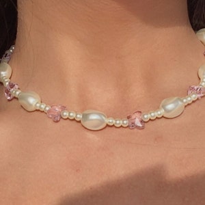 May include: A delicate pearl and pink crystal choker necklace. The necklace features small, round pearls and pink crystal accents.