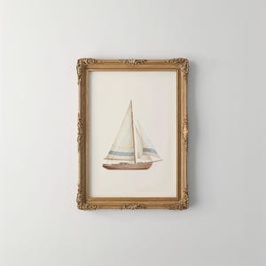 May include: A framed watercolor print of a sailboat. The boat is brown with white sails and blue stripes. The frame is ornate, gold-colored, and rectangular. The artwork is displayed against a white background.