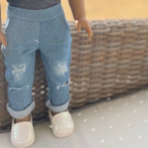 May include: A pair of light blue denim jeans with distressed details. The jeans are cuffed at the bottom and have a relaxed fit.