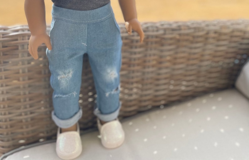 May include: A pair of light blue denim jeans with distressed details. The jeans are cuffed at the bottom and have a relaxed fit.