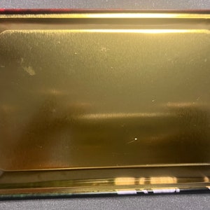 以下が含まれることがあります： 縁が高く、金色の金属製のトレイ。トレイはブラッシュ仕上げで、空です。