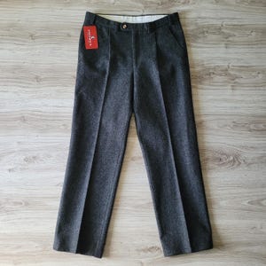 Può includere: Pantaloni in lana grigia con un'etichetta rossa che dice "Stetson".