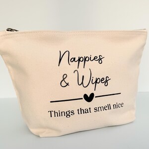 Peut inclure: Un sac en toile beige avec une fermeture &eacute;clair noire. Le sac porte l'inscription "Nappies & Wipes" au-dessus d'un c&oelig;ur et la phrase "Things that smell nice". Con&ccedil;u pour les essentiels de b&eacute;b&eacute;.