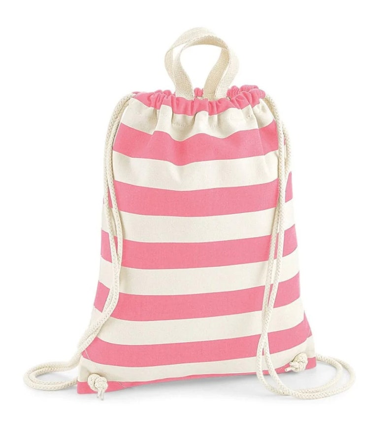 K&ouml;nnte beinhalten: Ein Kordelzugrucksack mit horizontalen rosa und cremewei&szlig;en Streifen. Die Tasche besteht aus Stoff mit einem Tragegriff und dicken, cremefarbenen Seilkordeln, die die &Ouml;ffnung oben zuziehen und an den unteren Ecken befestigt sind.