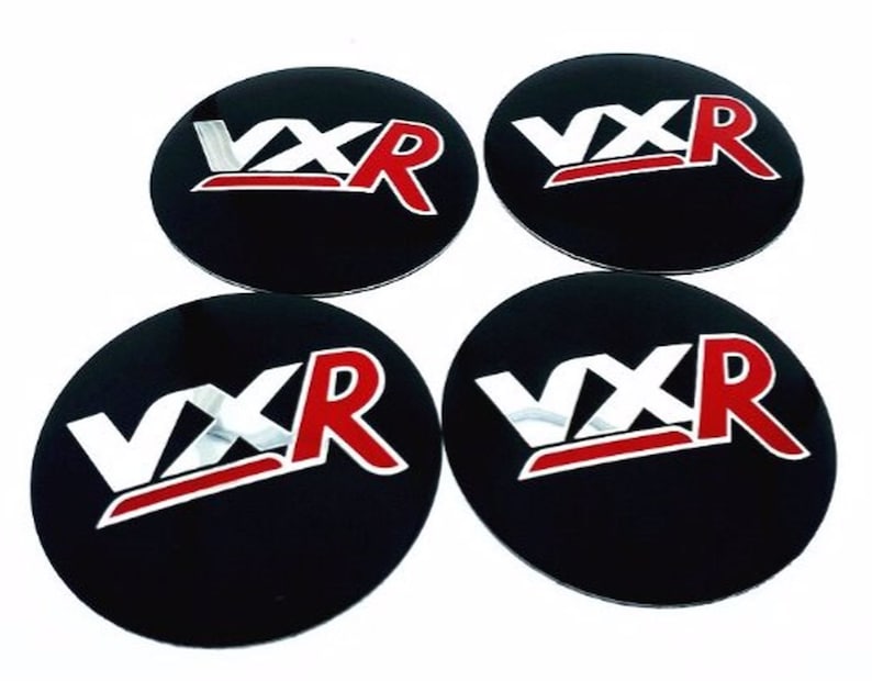 May include: Set of four black round car wheel centre caps with a silver and red "VXR" logo.