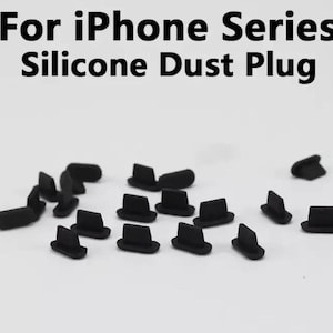 May include: A close-up of a pile of small black silicone dust plugs. The plugs are designed to fit into the charging ports of iPhones to prevent dust and debris from entering.