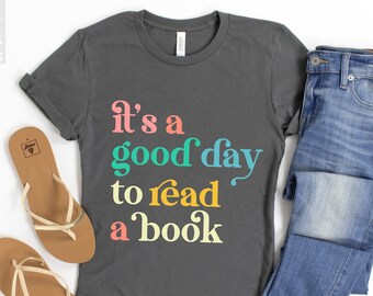 May include: A charcoal grey t-shirt with the text "It's a good day to read a book" in rainbow colors.