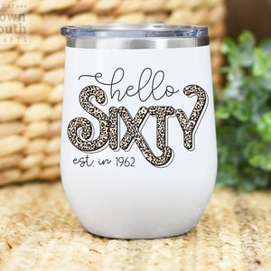 May include: White stainless steel wine tumbler with a leopard print design and the text "hello sixty est. in 1962".