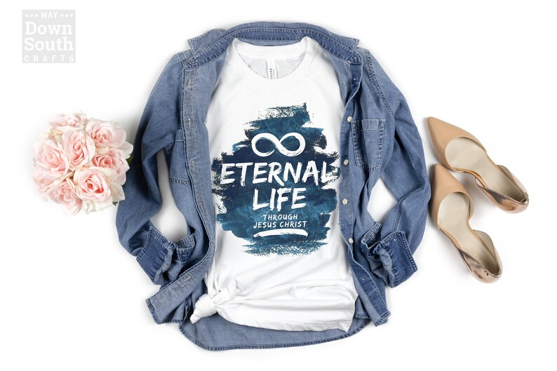 May include: White t-shirt with a blue watercolor design featuring the text "Eternal Life Through Jesus Christ" and an infinity symbol.
