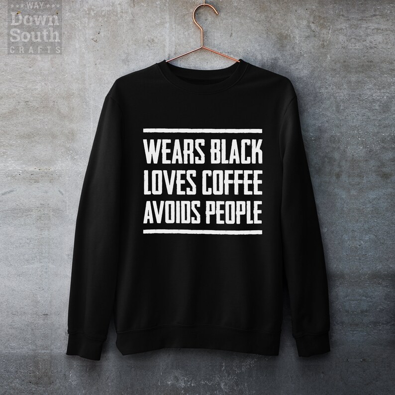May include: Black sweatshirt with white text that reads "Wears Black Loves Coffee Avoids People".
