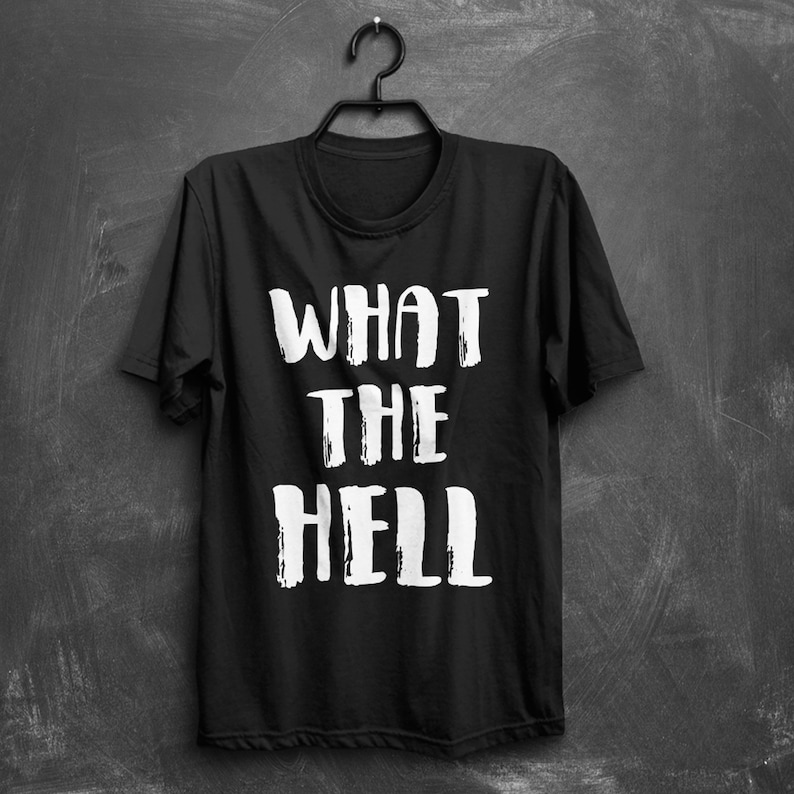 May include: Black t-shirt with white text that reads "WHAT THE HELL" in a bold, brushstroke font.