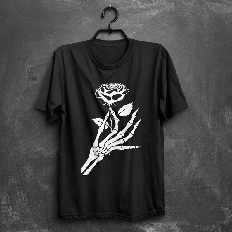 Puede incluir: Camiseta negra con un gr&aacute;fico blanco de una mano esquel&eacute;tica sosteniendo una rosa.