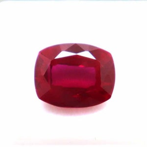 Peut inclure: Une pierre précieuse rouge foncé de taille coussin, présentée sur un fond blanc.
